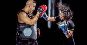 A woman boxing with a trainer in a gym, showcasing strength and focus.